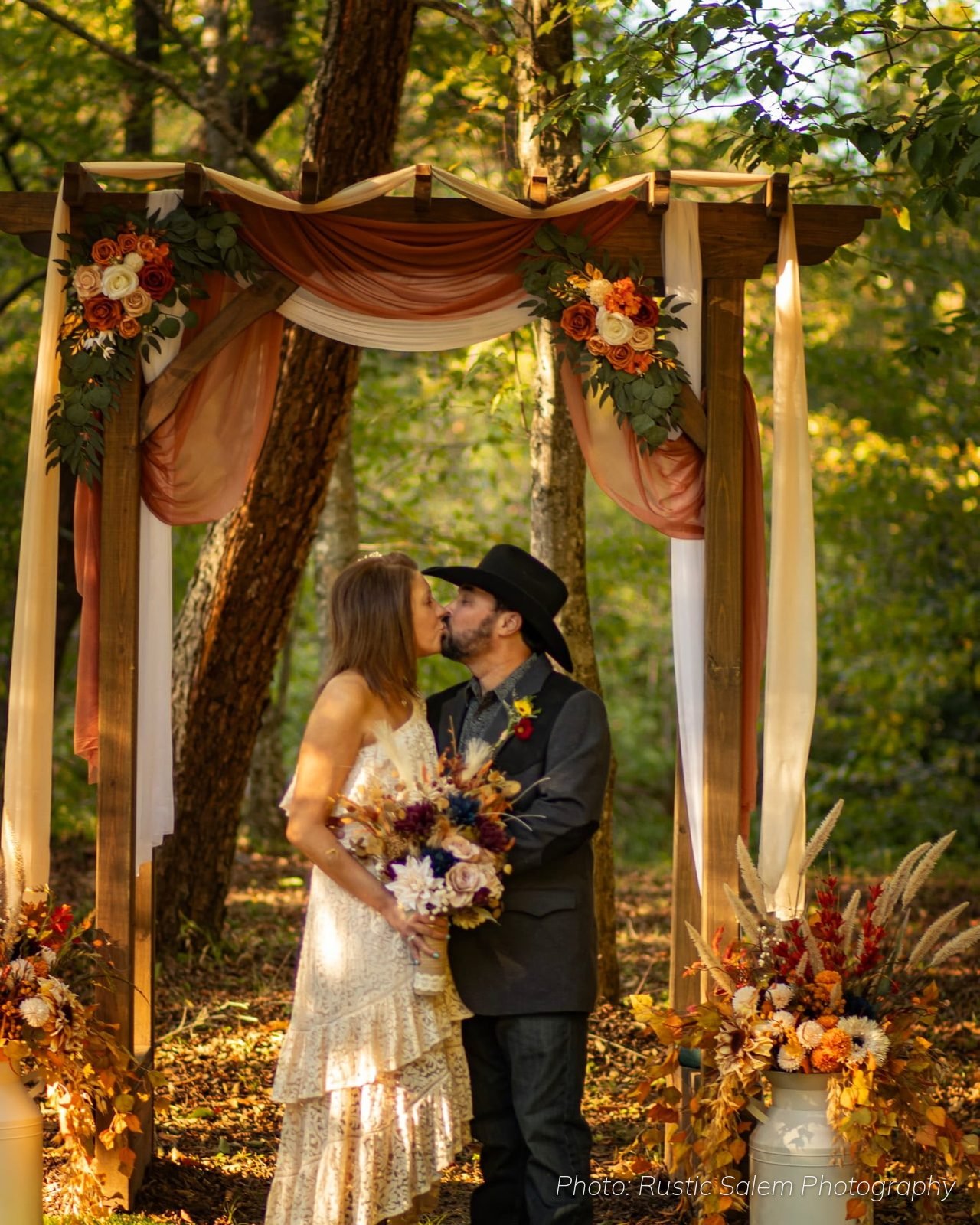 Bride and groom under the wooden ceremony arch at Riverside Farm Venue