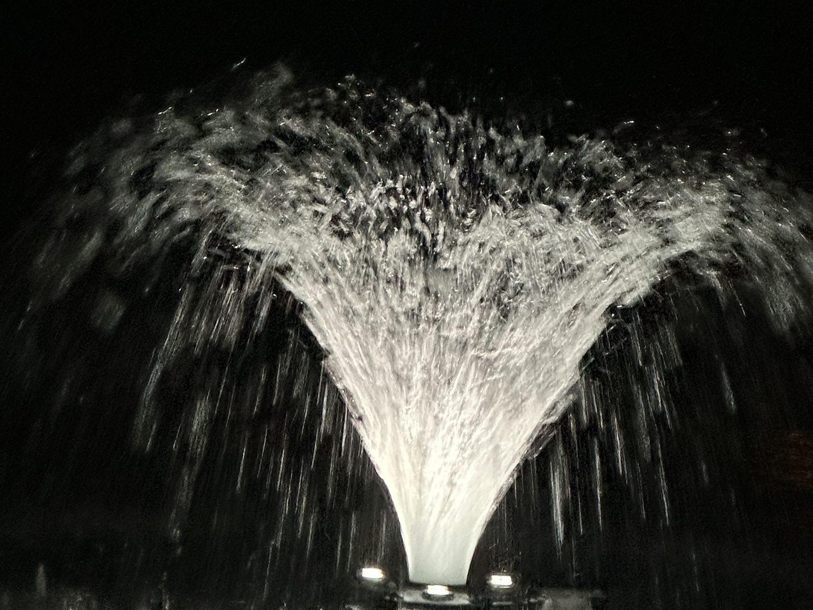 The pond fountain lit up at night at Riverside Farm Venue