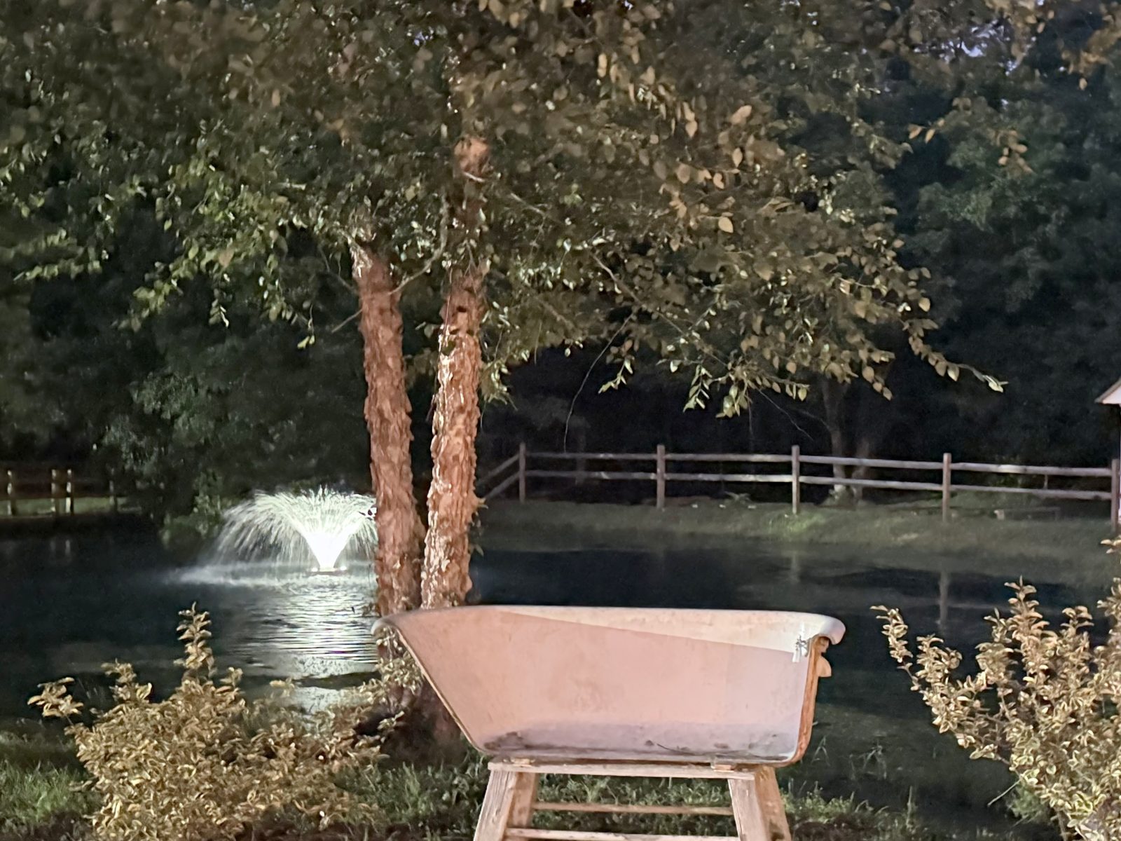 The pond and fountain at night beside a clawfoot tub planter at Riverside Farm Venue