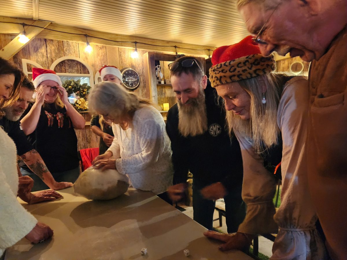 Friends gathered around a table laughing over a dice game at Riverside Farm Venue