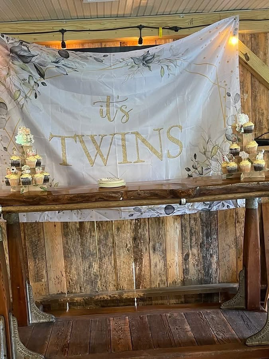 Twins baby shower set up at the rustic barn bar with string lights, cupcakes and an It&rsquo;s Twins banner at Riverside Farm Venue