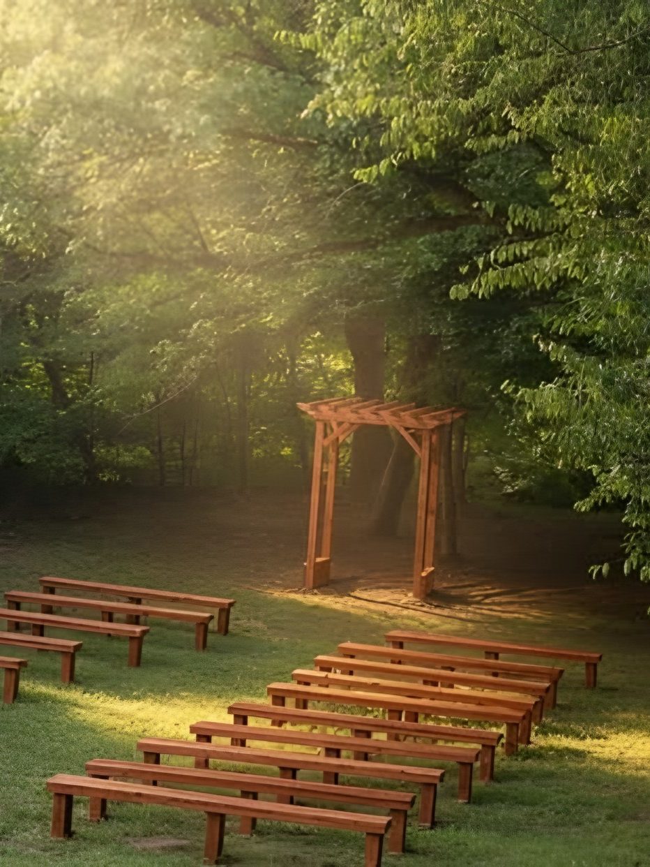 Rows of wooden benches facing the wooden ceremony arch in the sunlit woods