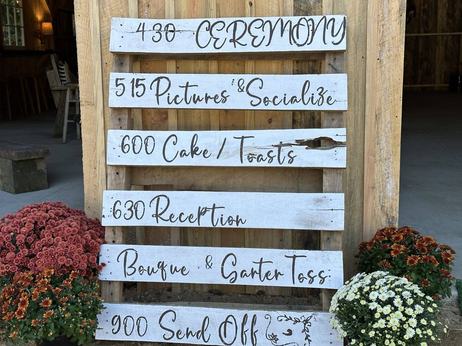 Hand-painted wooden wedding schedule sign with mums